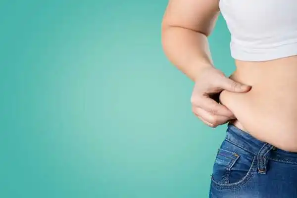 Image of woman pinching her love handles to show weight gain Oxted