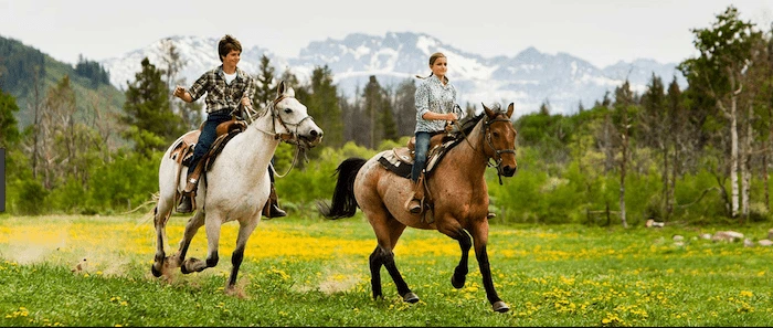 Confident plus-size woman riding Oxted a horse through a field with a smile on her face.